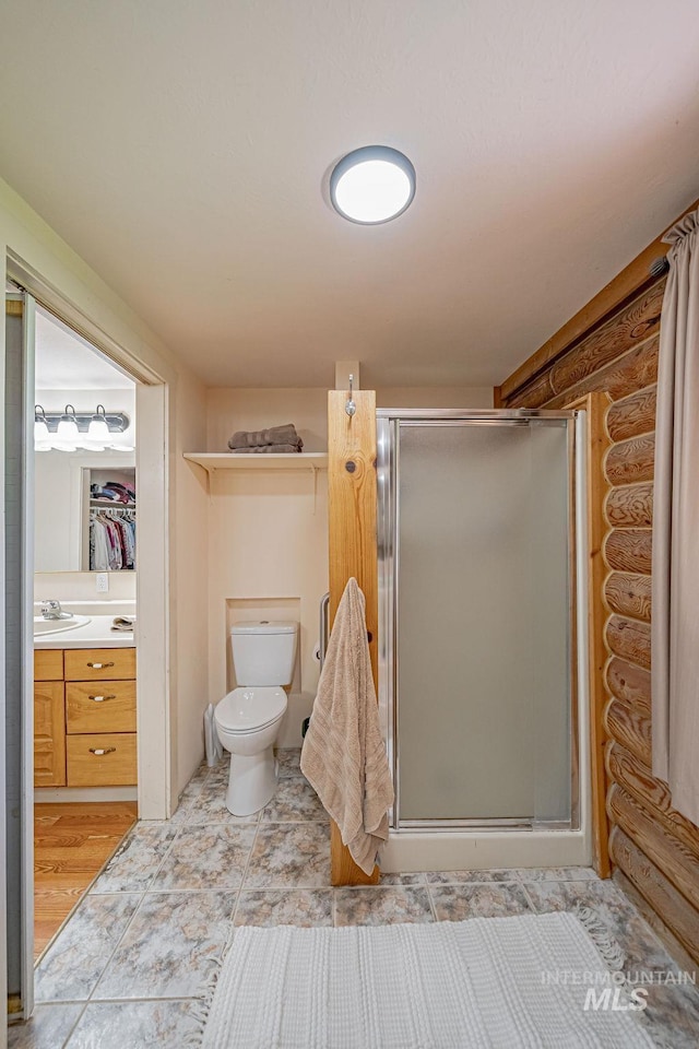 full bath featuring a stall shower, toilet, log walls, a walk in closet, and vanity