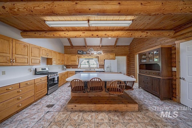 kitchen with a kitchen island, appliances with stainless steel finishes, a breakfast bar area, vaulted ceiling with beams, and light countertops