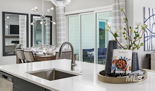 kitchen featuring a sink, open floor plan, light countertops, ornate columns, and stainless steel dishwasher