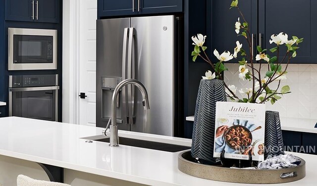 kitchen featuring blue cabinetry, appliances with stainless steel finishes, and light countertops