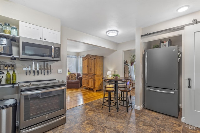 3233 8th St, Lewiston, ID 83501 - kitchen featuring stainless steel appliances, white cabinetry, a barn door, and baseboards