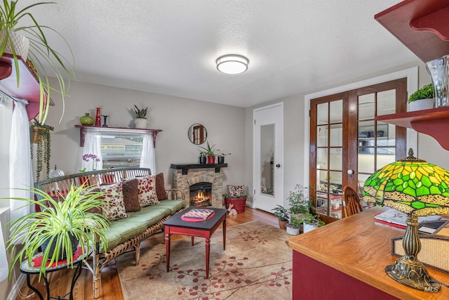 3233 8th St, Lewiston, ID 83501 - living room featuring wood finished floors, a textured ceiling, a stone fireplace, healthy amount of natural light, and french doors