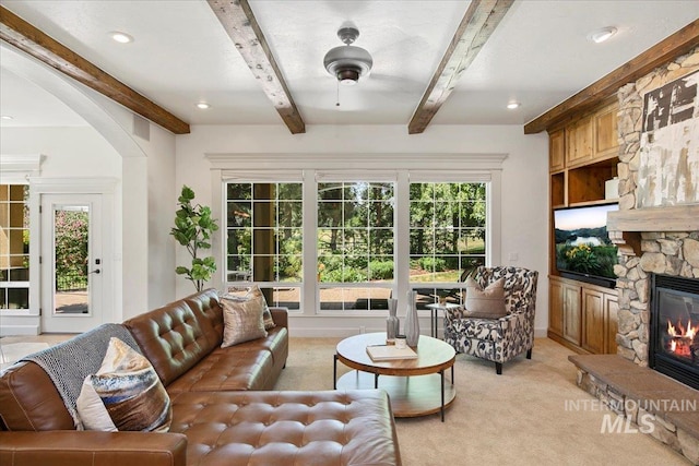 living room featuring light colored carpet, a fireplace, and beam ceiling