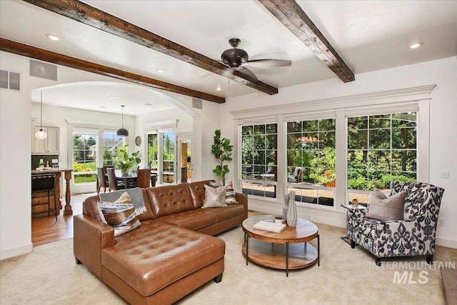 living room featuring beamed ceiling, ceiling fan, and light hardwood / wood-style flooring