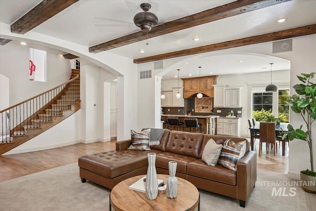 living room featuring ceiling fan, light wood-type flooring, and beam ceiling