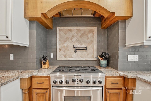 kitchen with white cabinetry, stainless steel range, tasteful backsplash, and light stone countertops