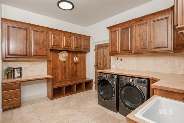 laundry area featuring sink, light tile patterned floors, washing machine and dryer, and cabinets