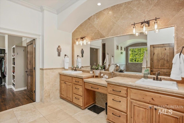 bathroom with tile patterned floors, ornamental molding, vanity, and tile walls