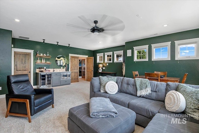 living room with indoor bar, light colored carpet, wine cooler, and ceiling fan