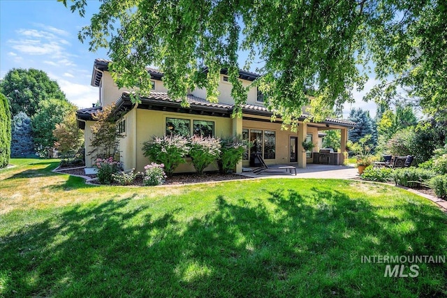 rear view of house with a patio and a lawn