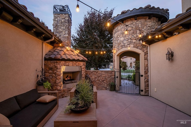 patio terrace at dusk with an outdoor stone fireplace