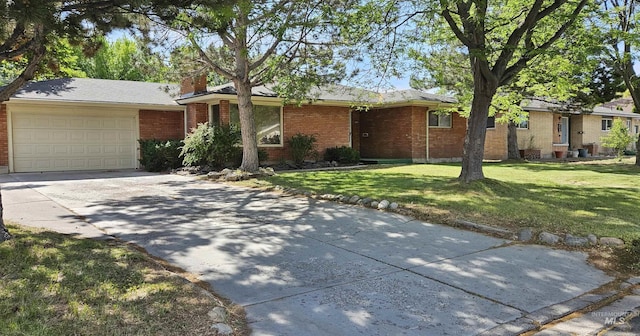 604 Monte Vis, Twin Falls, ID 83301 - view of front facade featuring concrete driveway, a front yard, an attached garage, a chimney, and brick siding