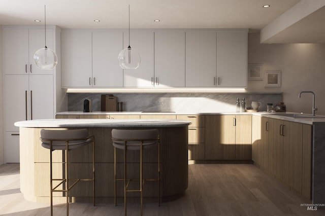 kitchen featuring a breakfast bar, a sink, light countertops, modern cabinets, and pendant lighting