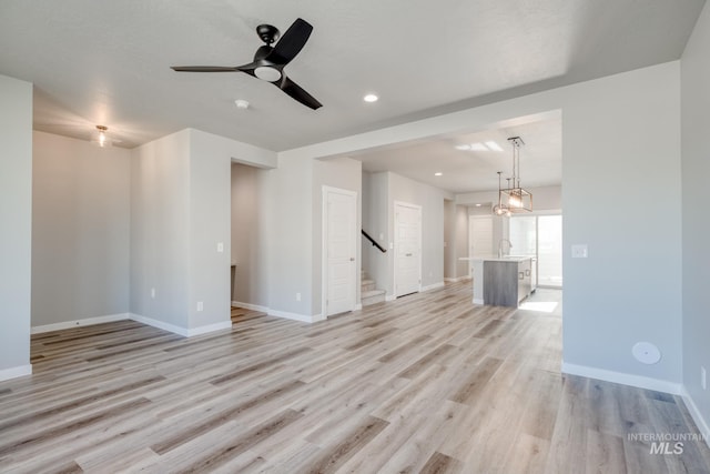 3542 W Littleton Dr, Meridian, ID 83642 - unfurnished living room featuring light wood-type flooring, baseboards, a ceiling fan, stairs, and recessed lighting