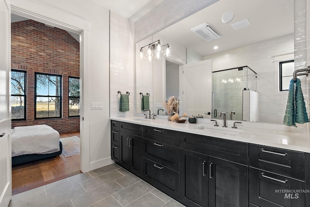 bathroom featuring brick wall, vanity, and a shower with shower door