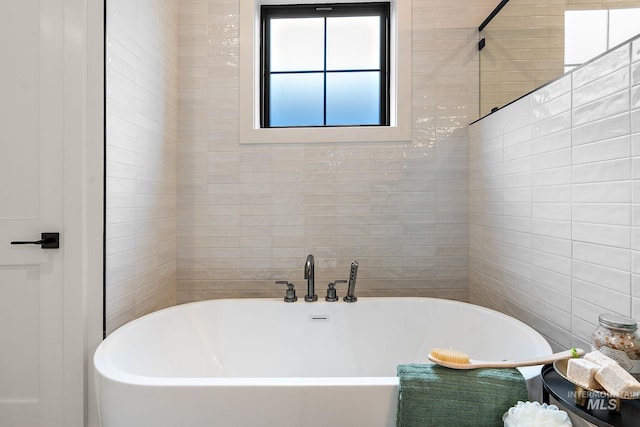 bathroom with a tub and tile walls