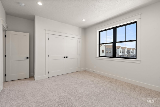 unfurnished bedroom featuring light colored carpet, a closet, and a textured ceiling