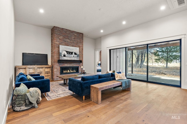 living room with a fireplace, light hardwood / wood-style flooring, and a textured ceiling