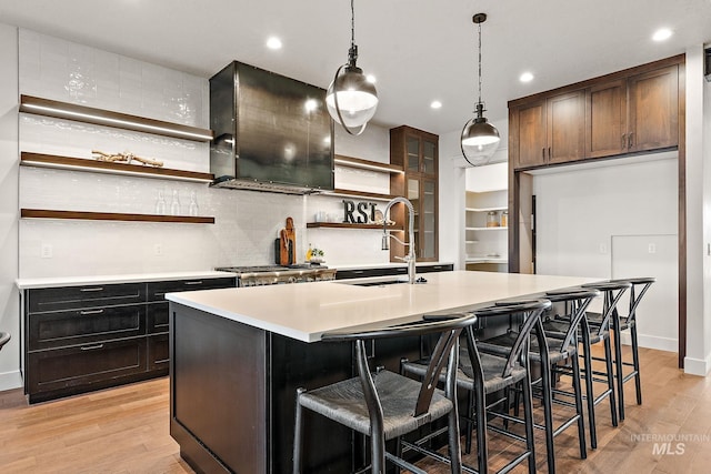 kitchen featuring a kitchen island with sink, sink, pendant lighting, and light hardwood / wood-style flooring