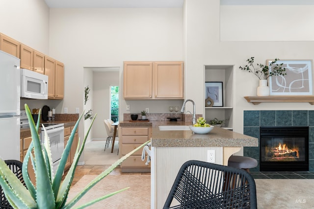 6460 S Lodgepole Pl, Boise, ID 83716 - kitchen with white appliances, a sink, light brown cabinets, a high ceiling, and a tiled fireplace
