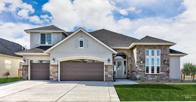 view of front of property with stucco siding, concrete driveway, a front lawn, and a shingled roof