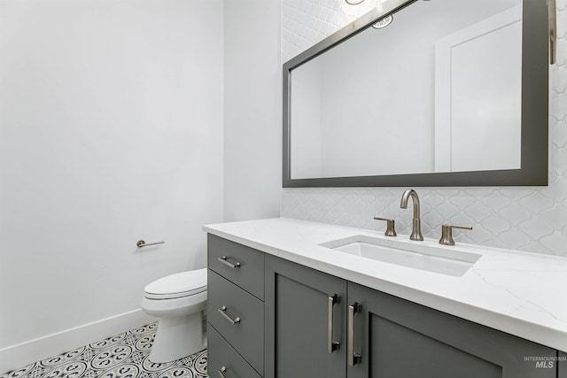 bathroom featuring vanity, baseboards, decorative backsplash, tile patterned floors, and toilet