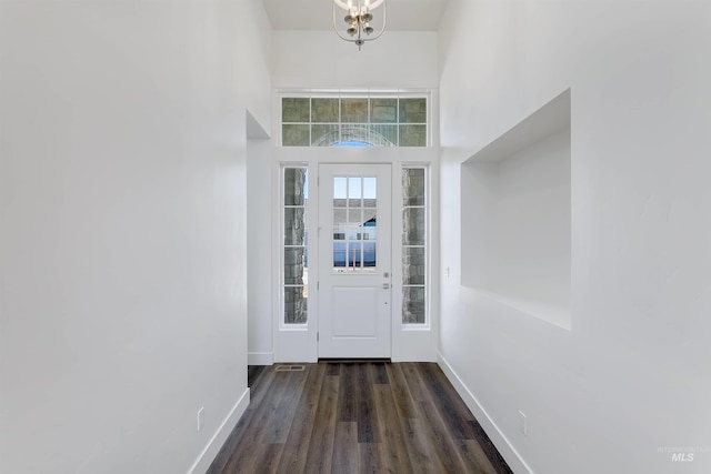 entryway featuring an inviting chandelier, a high ceiling, baseboards, and wood finished floors