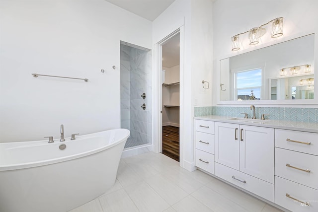 bathroom featuring a spacious closet, a shower stall, backsplash, a soaking tub, and vanity