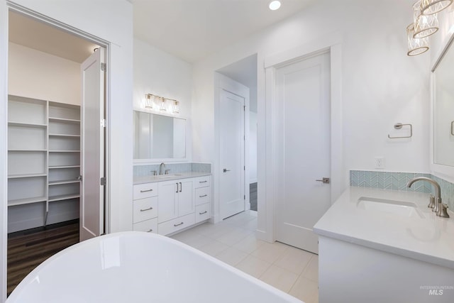 full bathroom with a soaking tub, two vanities, tile patterned floors, and a sink