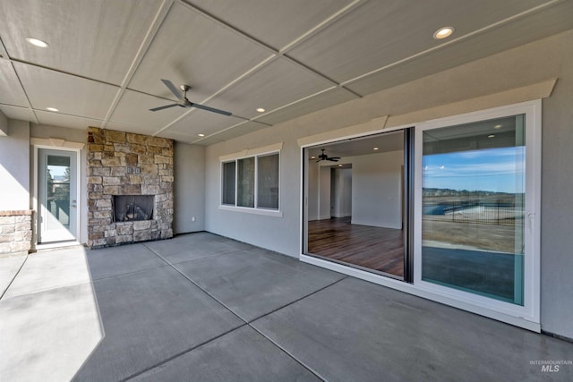 view of patio featuring an outdoor stone fireplace and ceiling fan