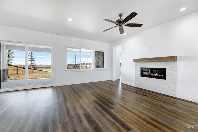 unfurnished living room featuring recessed lighting, baseboards, a glass covered fireplace, and dark wood-style flooring