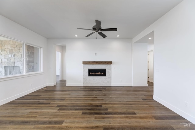 unfurnished living room featuring dark wood finished floors, recessed lighting, baseboards, and a lit fireplace