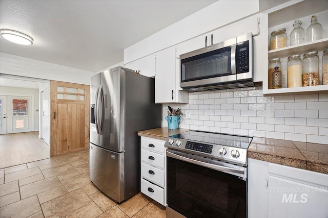 kitchen with backsplash, tile countertops, appliances with stainless steel finishes, white cabinets, and open shelves