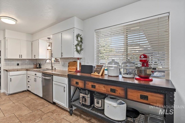 kitchen with backsplash, white cabinetry, stainless steel dishwasher, and a sink