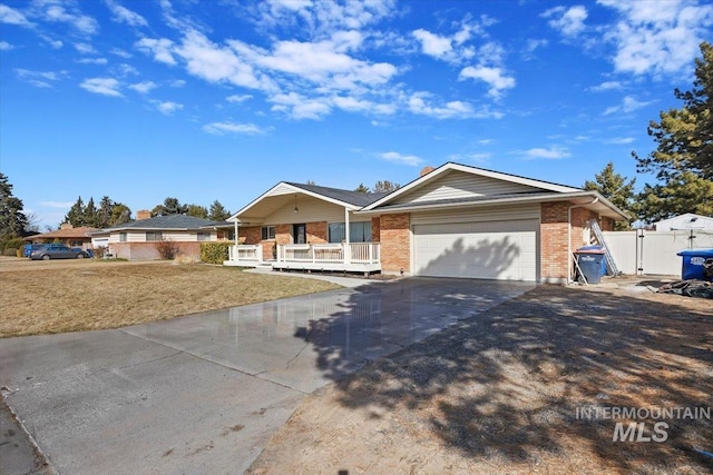 single story home with a gate, driveway, an attached garage, covered porch, and brick siding