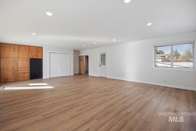 unfurnished living room featuring recessed lighting, light wood-style floors, and baseboards