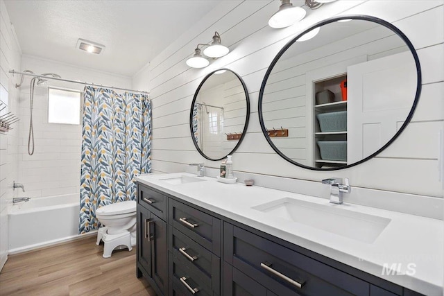 bathroom with a sink, toilet, wood finished floors, and double vanity