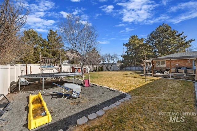 view of yard featuring a fenced backyard, a playground, and a trampoline