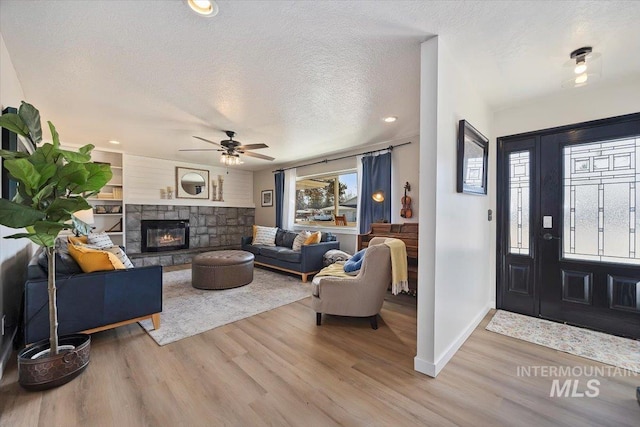 foyer with baseboards, a textured ceiling, wood finished floors, and a fireplace