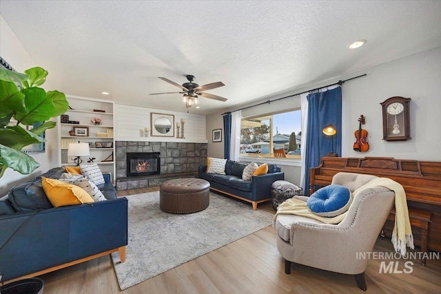 living area featuring a ceiling fan, a textured ceiling, wood finished floors, recessed lighting, and a fireplace