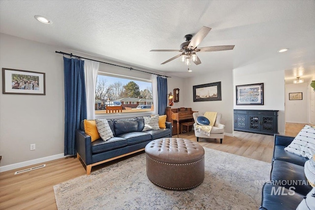 living area with visible vents, a textured ceiling, baseboards, and wood finished floors