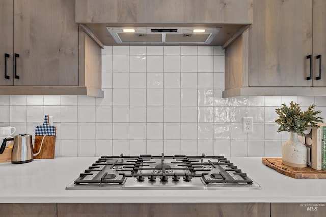 kitchen with ventilation hood, stainless steel gas cooktop, and backsplash