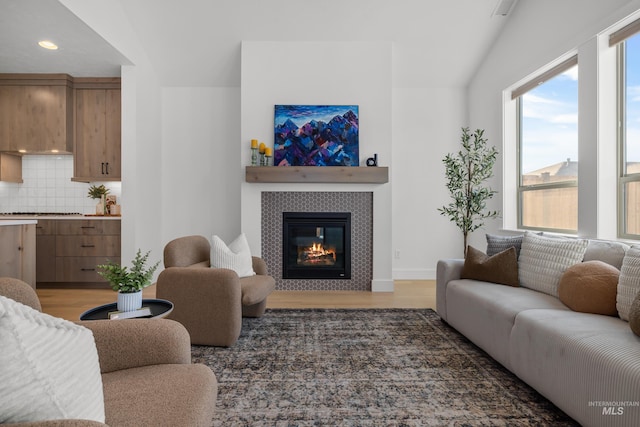 living room featuring a tile fireplace, vaulted ceiling, and dark hardwood / wood-style flooring