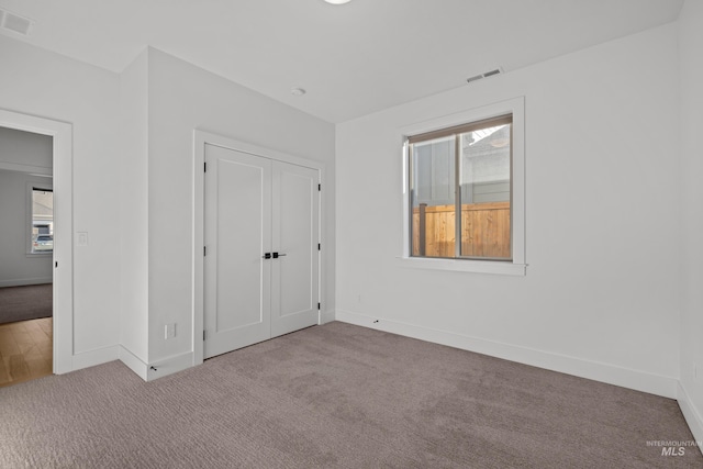 unfurnished bedroom featuring light colored carpet and a closet