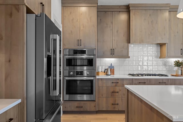 kitchen with stainless steel appliances, decorative backsplash, and light hardwood / wood-style flooring