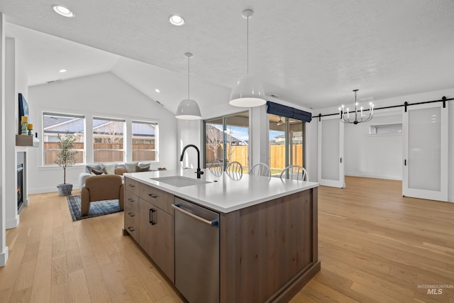 kitchen with sink, a center island with sink, stainless steel dishwasher, and a textured ceiling