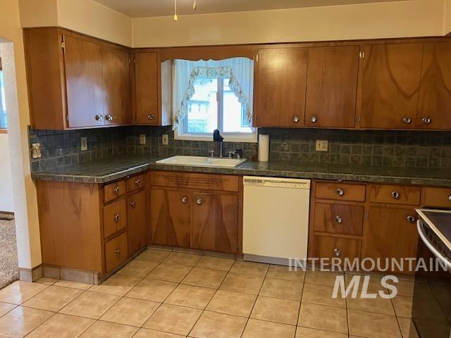 kitchen featuring white dishwasher, range with electric cooktop, sink, and tasteful backsplash