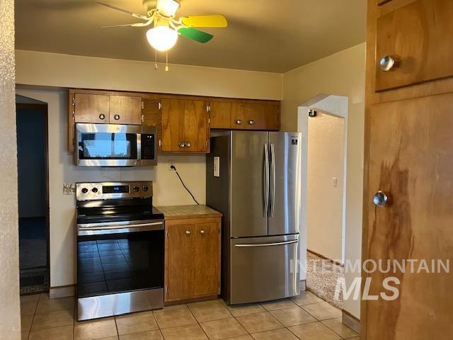 kitchen with ceiling fan, light tile patterned flooring, and stainless steel appliances