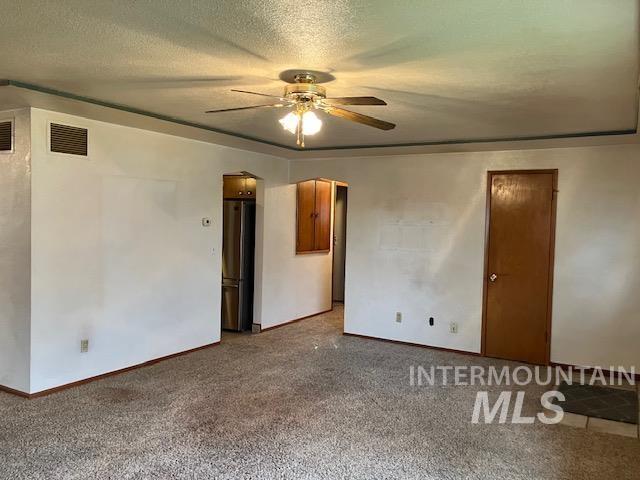 carpeted empty room featuring a textured ceiling and ceiling fan