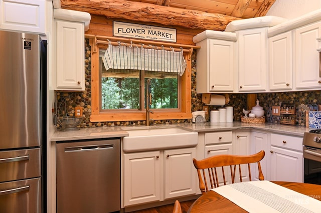 kitchen featuring tasteful backsplash, appliances with stainless steel finishes, a sink, and white cabinets